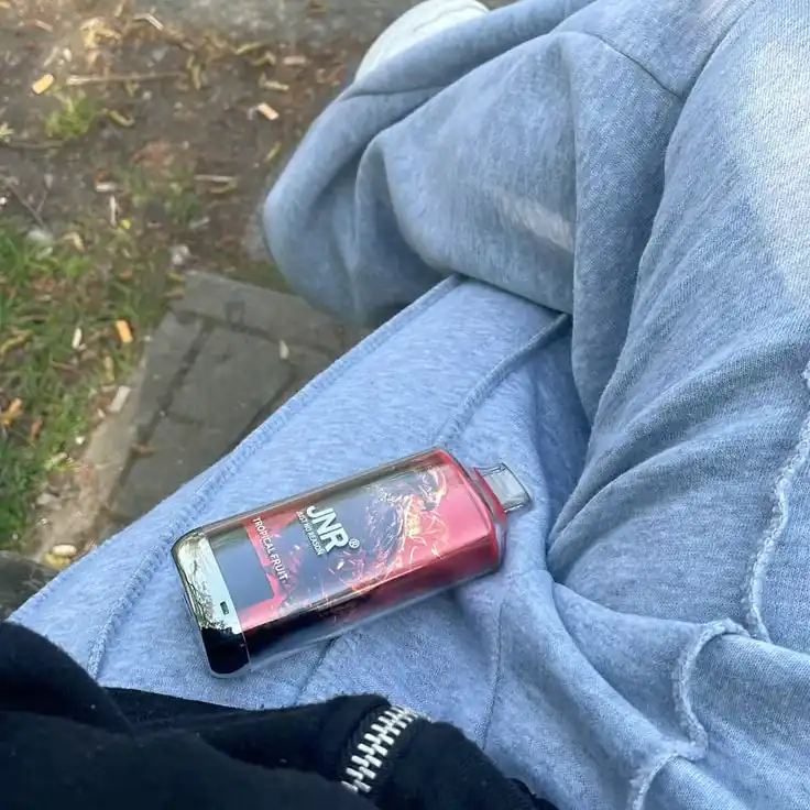 Puff JNR Falcon X rangée dans la poche d'un sweat à capuche