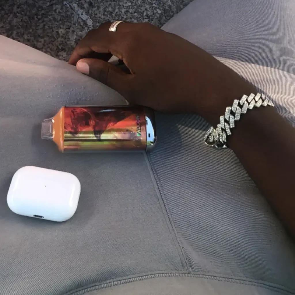 Puff Razz Bar et boîtier d'écouteurs posés sur un pantalon gris